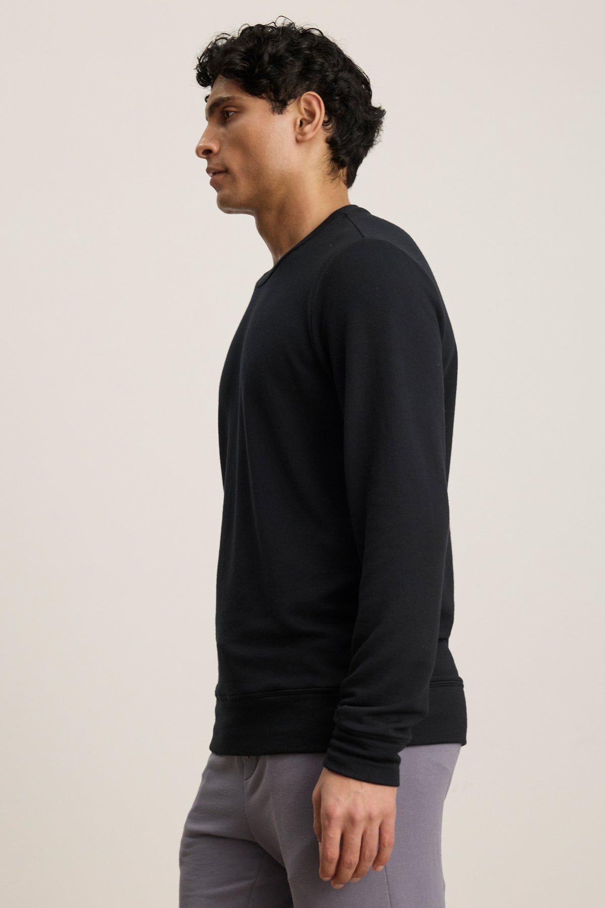 A man stands in profile against a plain background, wearing the SOREN PULLOVER by Velvet by Graham & Spencer and light gray pants.-39841106657473