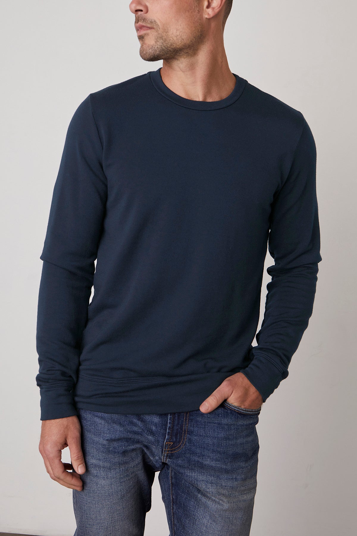   A person wearing a SOREN PULLOVER by Velvet by Graham & Spencer and jeans stands against a plain background, looking to the side. 