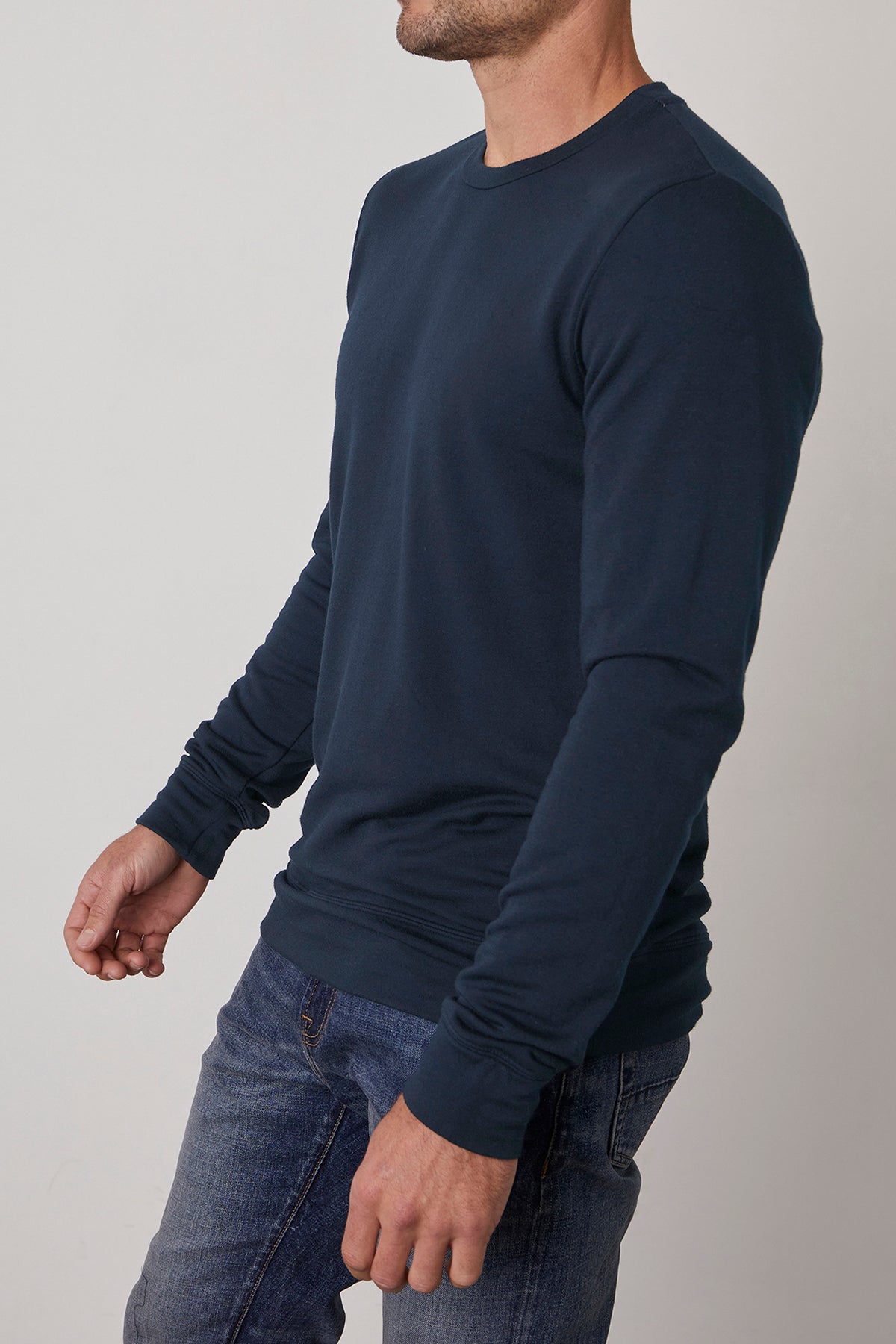   A man wearing the SOREN PULLOVER by Velvet by Graham & Spencer and jeans stands against a plain background, facing slightly sideways. 