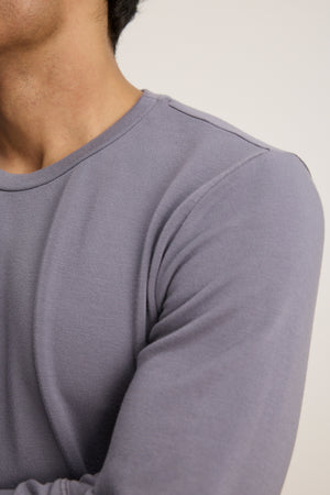 A person wearing the Velvet by Graham & Spencer SOREN PULLOVER, a luxe fleece long-sleeve light purple top, with arms crossed and shown from shoulders to mid-chest.