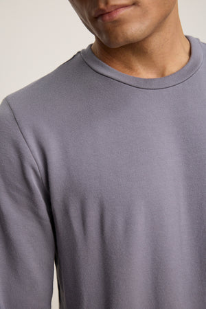 A person is shown from shoulders to mid-chest wearing the SOREN PULLOVER by Velvet by Graham & Spencer, a light gray, long-sleeve crew neck.