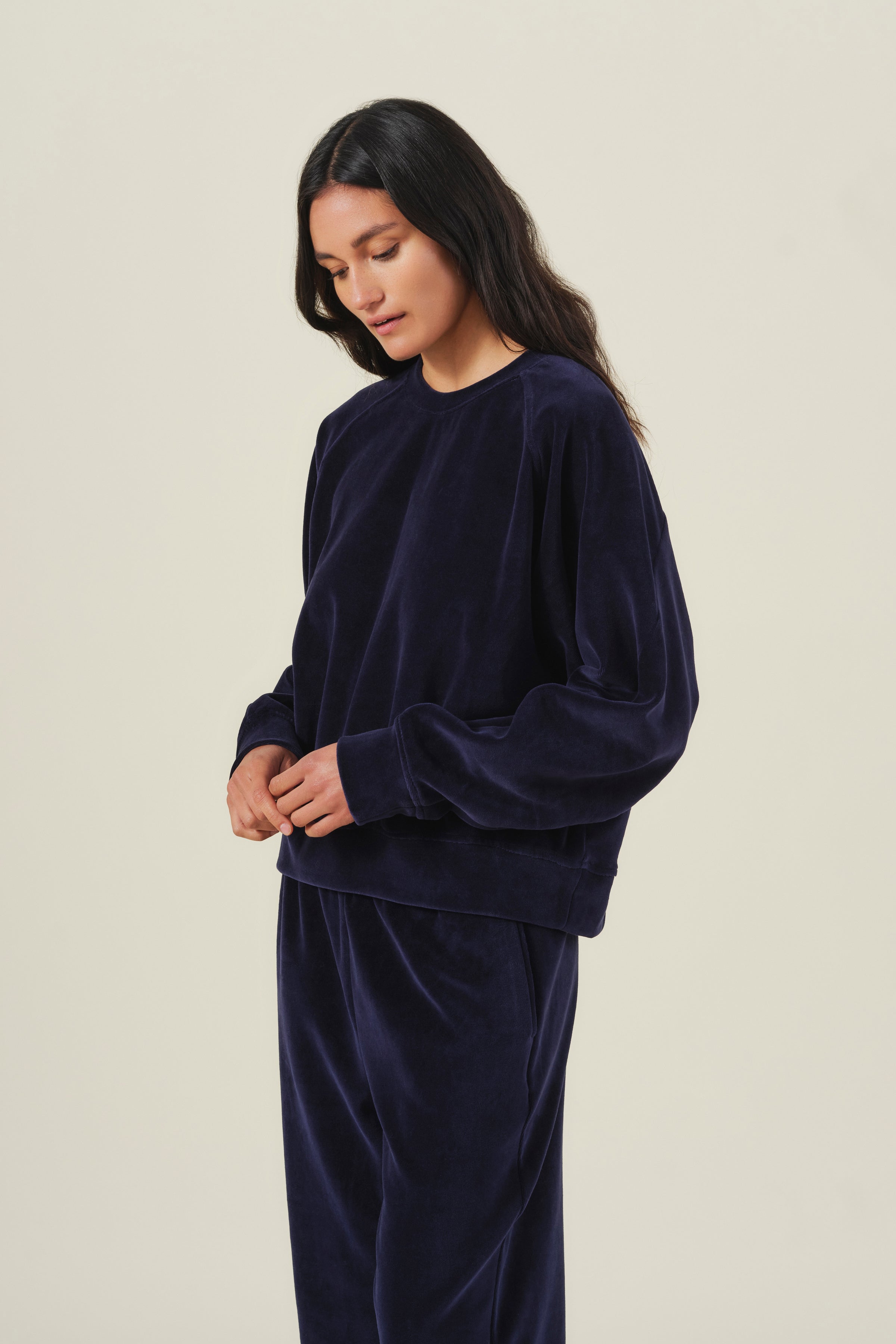 A person wears a long-sleeved navy CALLIE VELOUR SWEATSHIRT and matching pants as part of a loungewear set.