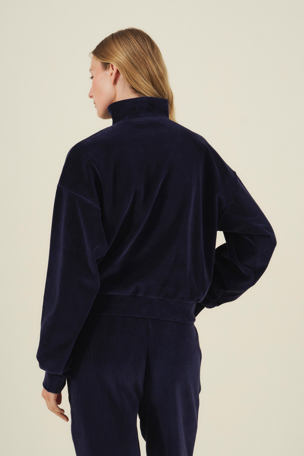 A person seen from behind wearing a navy blue DANICA VELOUR HALF-ZIP SWEATSHIRT with a mock neck.