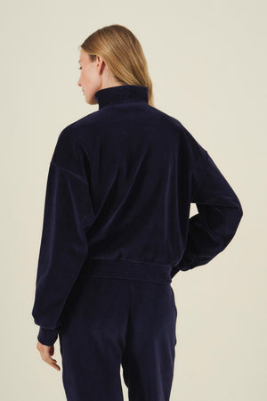 A person seen from behind wearing a navy blue DANICA VELOUR HALF-ZIP SWEATSHIRT with a mock neck.