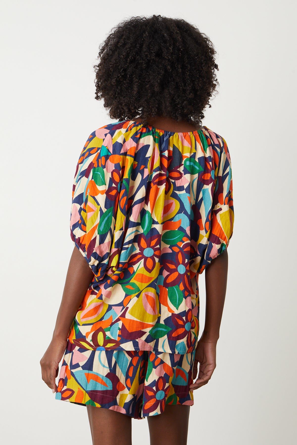   The back view of a woman wearing a Velvet by Graham & Spencer ROBIN PRINTED LINEN TOP and Josie shorts 