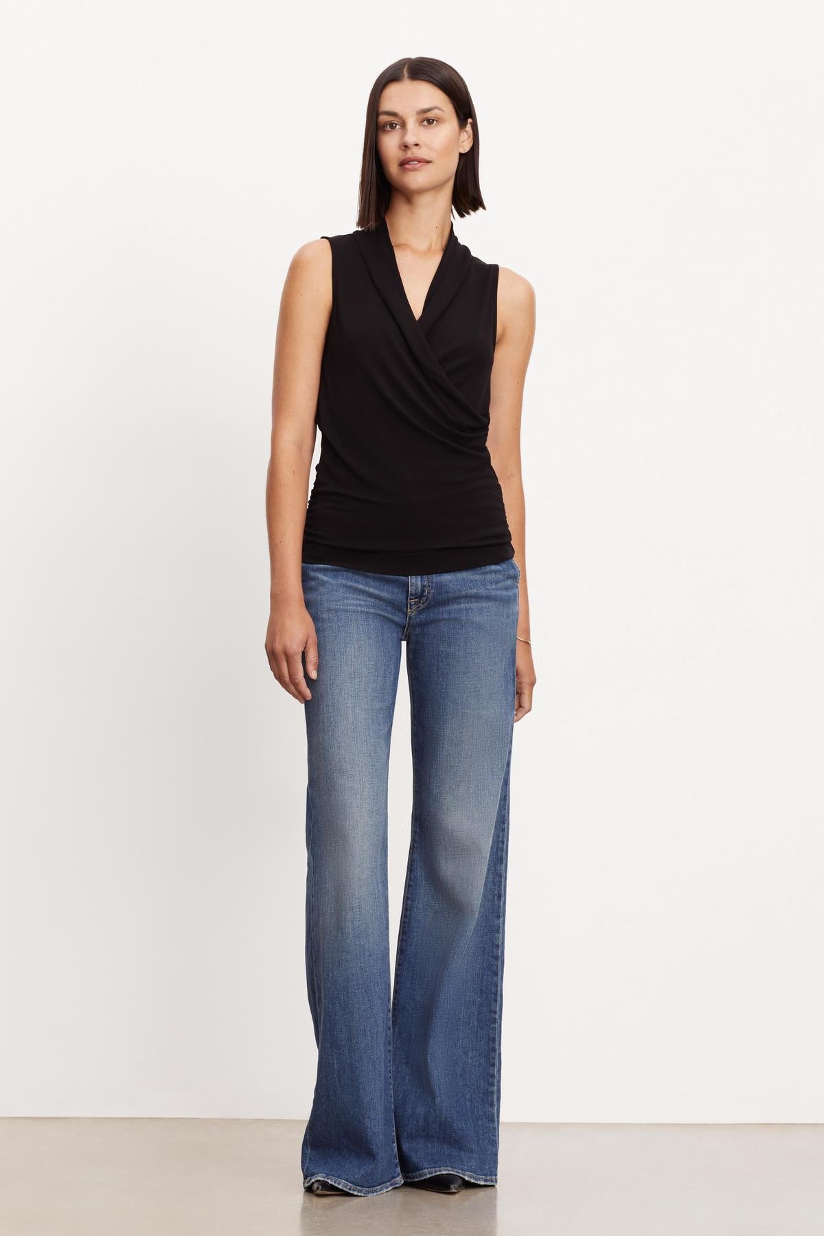   A woman wearing flared jeans and the DORTHY WRAP TANK TOP by Velvet by Graham & Spencer. 