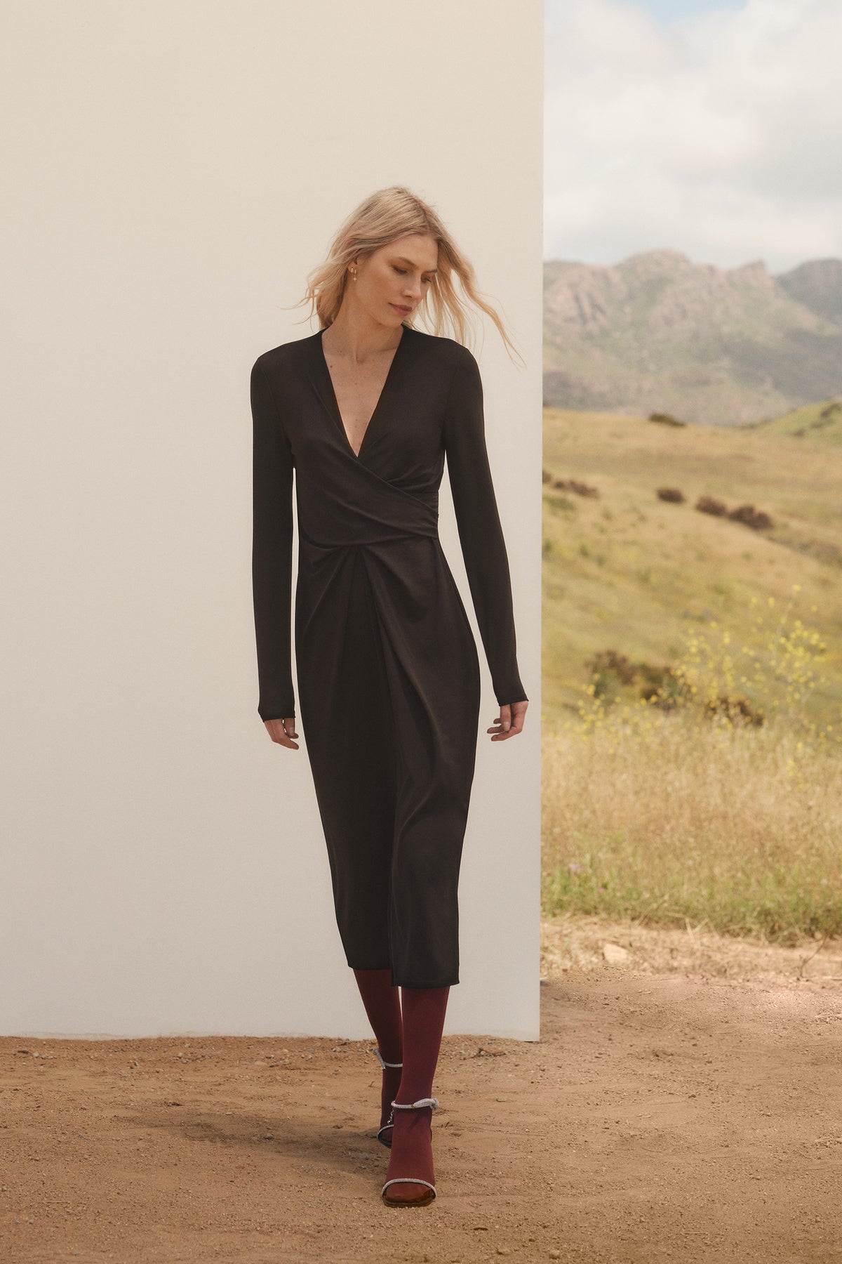 A woman in a Velvet by Graham & Spencer ELIANA WRAP MIDI DRESS standing in a field.-35654460539073