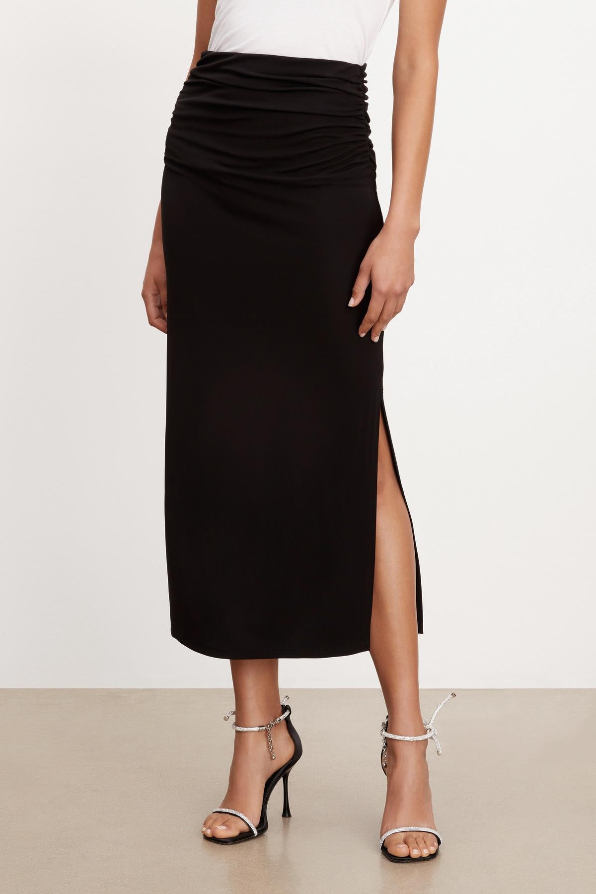 A woman wearing a Hilton Maxi Skirt with a slit by Velvet by Graham & Spencer.-35696219390145