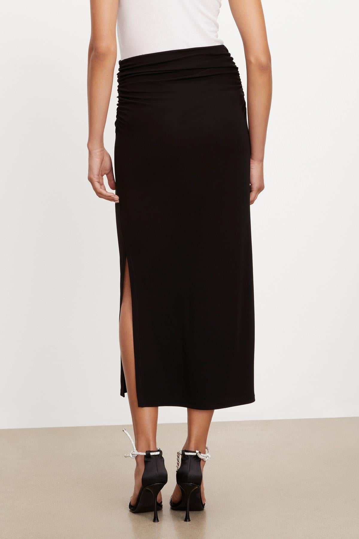 The back view of a woman wearing a Hilton Maxi Skirt by Velvet by Graham & Spencer.-35696219422913