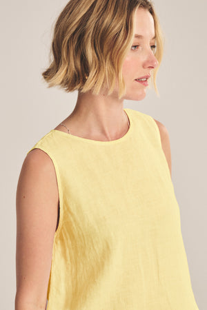 A woman with short blonde hair is wearing the MAXINE LINEN TOP by Velvet by Graham & Spencer in yellow, looking to the side against a neutral background.