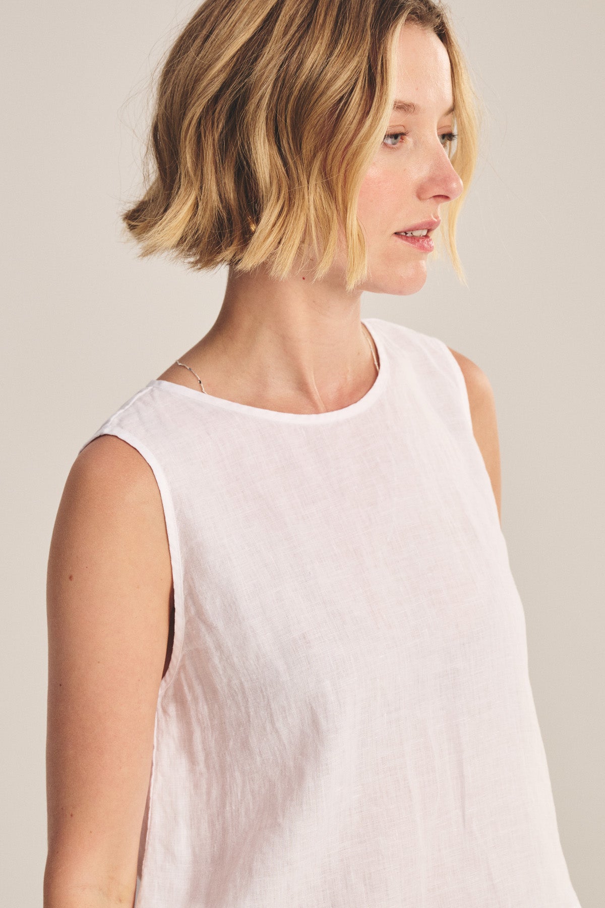 A woman with short blonde hair wears the MAXINE LINEN TOP by Velvet by Graham & Spencer, a sleeveless lightweight linen blouse, and looks slightly to the side against a neutral background.-41089021247681