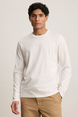 A man wearing the Velvet by Graham & Spencer ALFIE TEE and tan pants stands against a neutral background, looking directly at the camera.