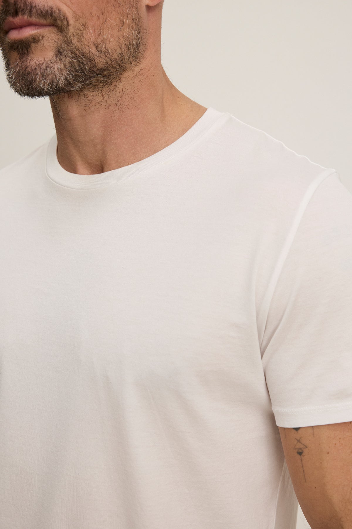 A man is shown from the shoulders up against a neutral background, wearing the FRANKIE TEE by Velvet by Graham & Spencer—a plain white t-shirt with a classic crew neckline.-39450521731265