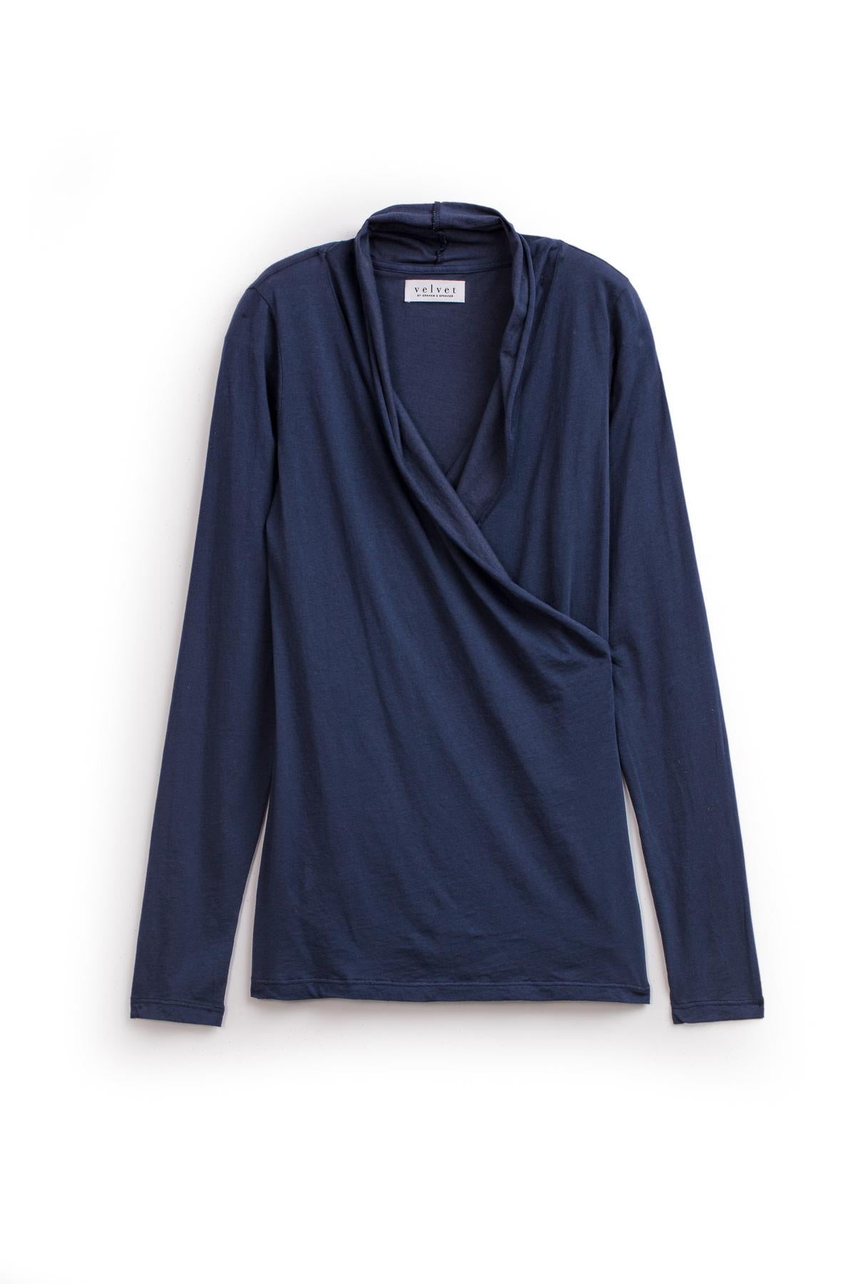   The Velvet by Graham & Spencer MERI TEE, a gauzy whisper fabric top featuring long sleeves, a V-neckline, and cross-over wrap detail in navy blue, displayed against a plain white background. 