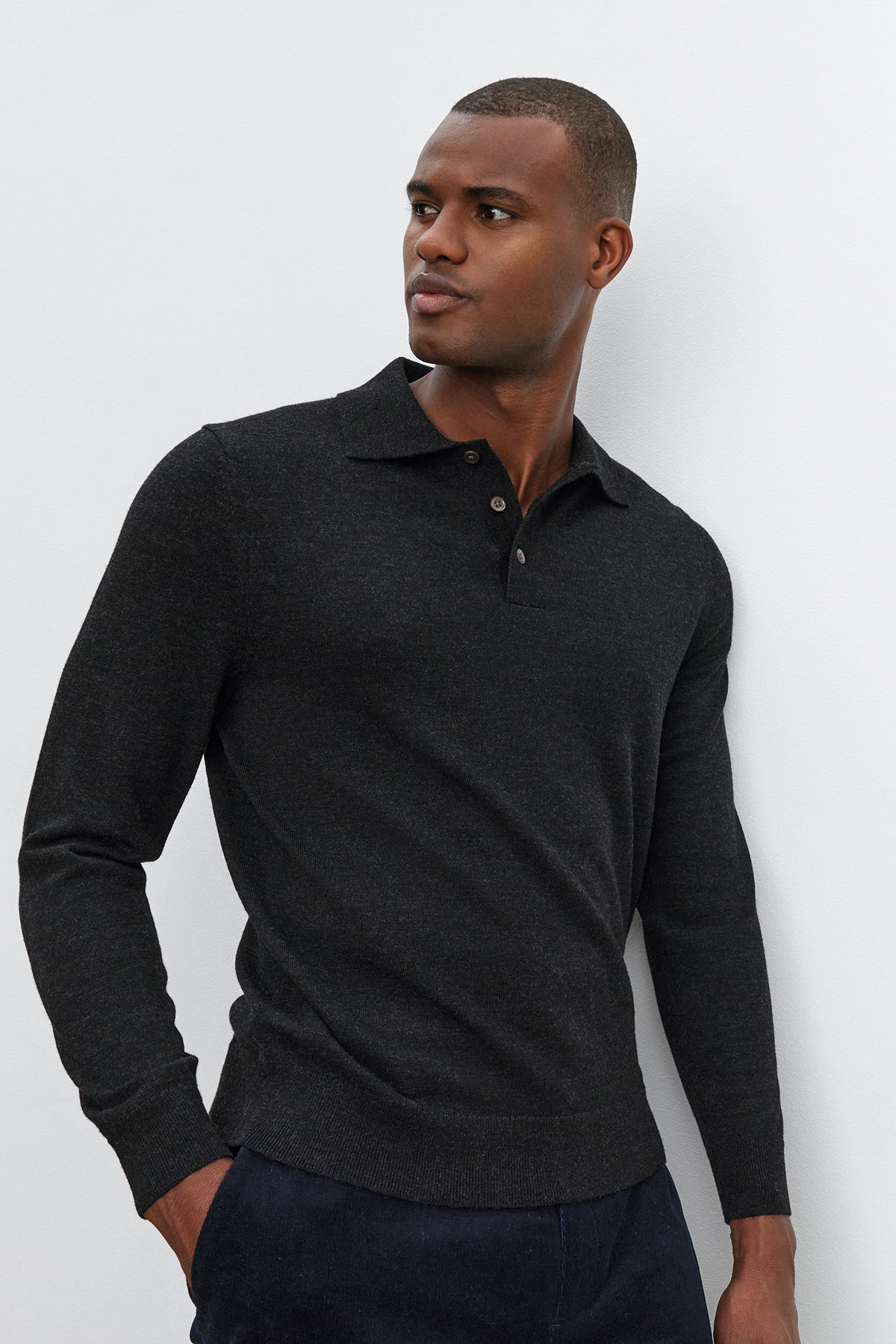   A man wearing a dark ARTHUR SWEATER POLO by Velvet by Graham & Spencer stands against a plain light-colored background, looking to his left. 