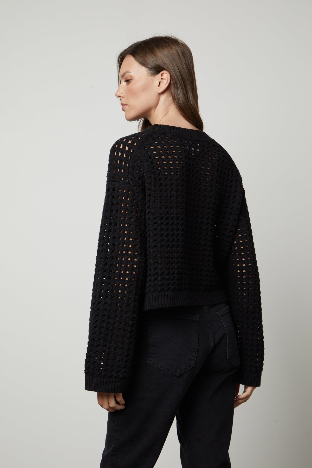   The back view of a woman wearing a Velvet by Graham & Spencer SAMMIE MESH KNIT CREW NECK SWEATER. 