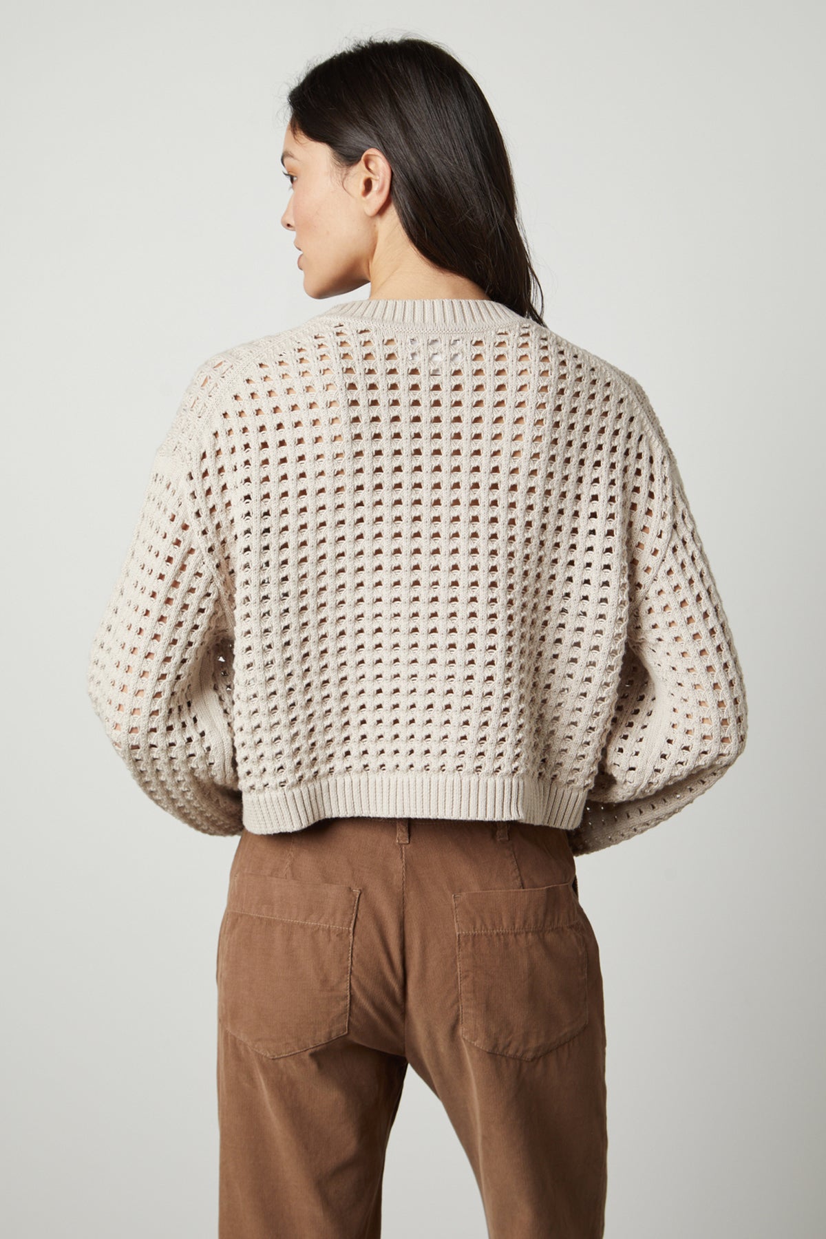   The back view of a woman wearing a Velvet by Graham & Spencer SAMMIE MESH KNIT CREW NECK SWEATER and brown pants. 