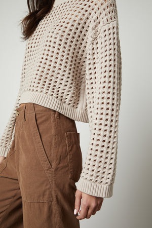 The model is wearing the Velvet by Graham & Spencer SAMMIE MESH KNIT CREW NECK SWEATER and brown pants.
