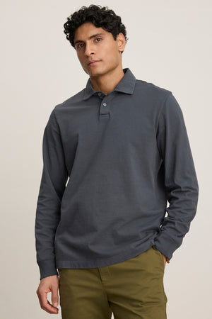 Someone stands against a plain light background wearing the FLINT POLO in dark grey cotton jersey with ribbed cuffs by Velvet by Graham & Spencer, paired with olive green pants.