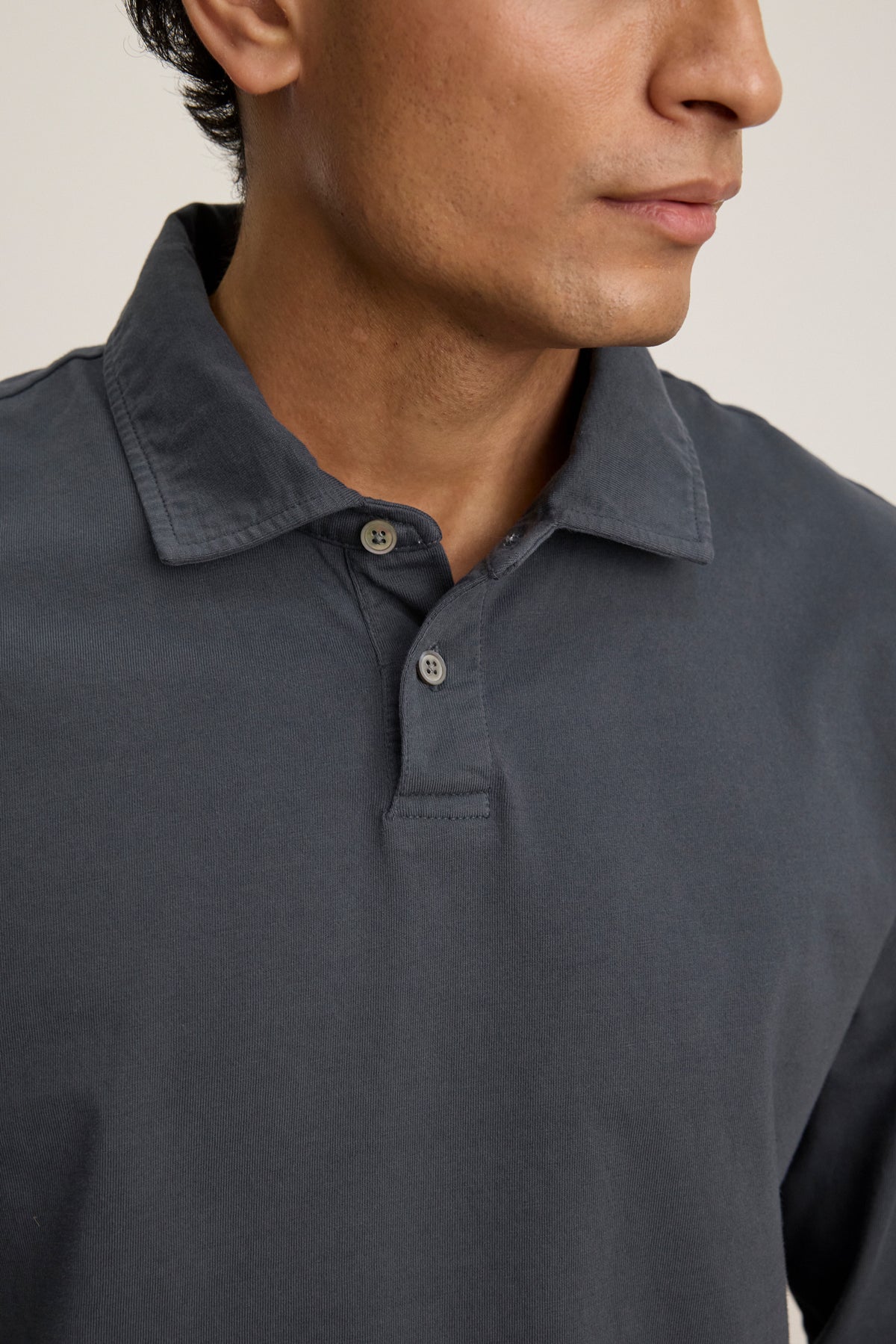 A person wearing the Velvet by Graham & Spencer FLINT POLO in dark grey cotton jersey, shown from the shoulders up and facing slightly to the right.-39680471597249
