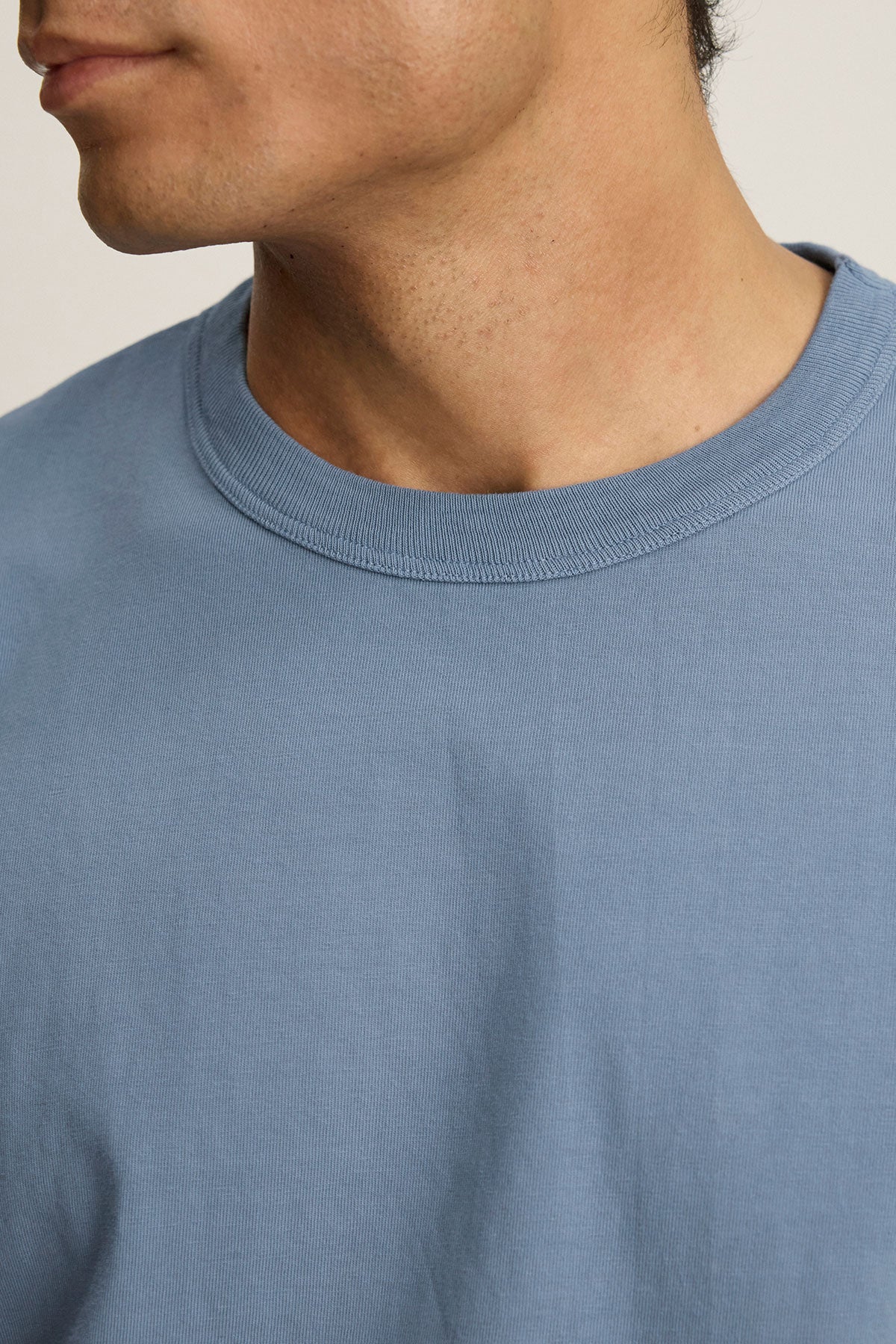 Close-up of a person wearing the WELLS TEE by Velvet by Graham & Spencer, a light blue cotton jersey crewneck, with the lower half of the face and neck visible.-39808332890305