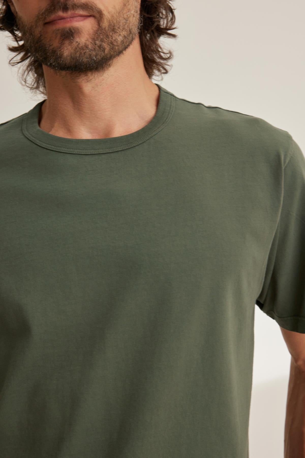 A bearded person wearing a Velvet by Graham & Spencer WELLS TEE in plain green is partially visible against a neutral background.-38643375931585