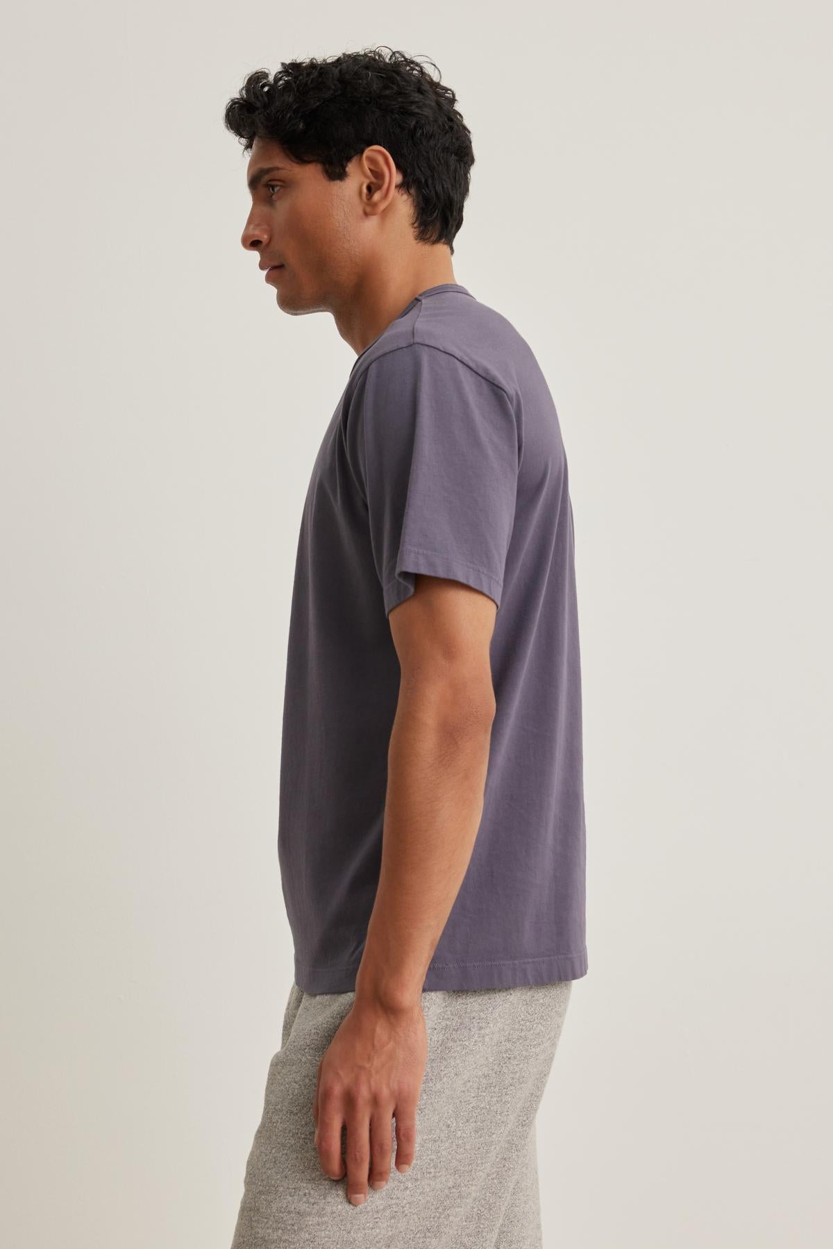 A person with short hair stands in profile, wearing a WELLS TEE by Velvet by Graham & Spencer and light gray shorts against a plain background.-38643375866049