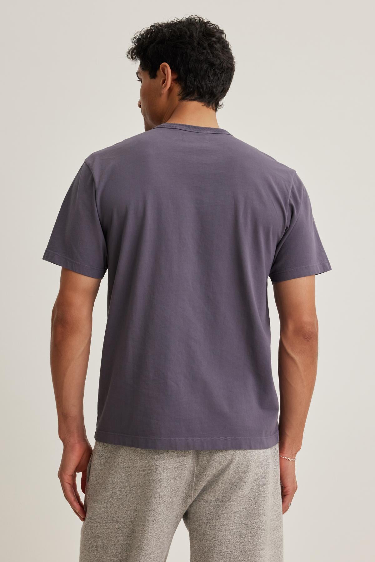 A person wearing the WELLS TEE by Velvet by Graham & Spencer and light gray pants is standing with their back to the camera.-38643375833281