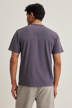 A person wearing the WELLS TEE by Velvet by Graham & Spencer and light gray pants is standing with their back to the camera.