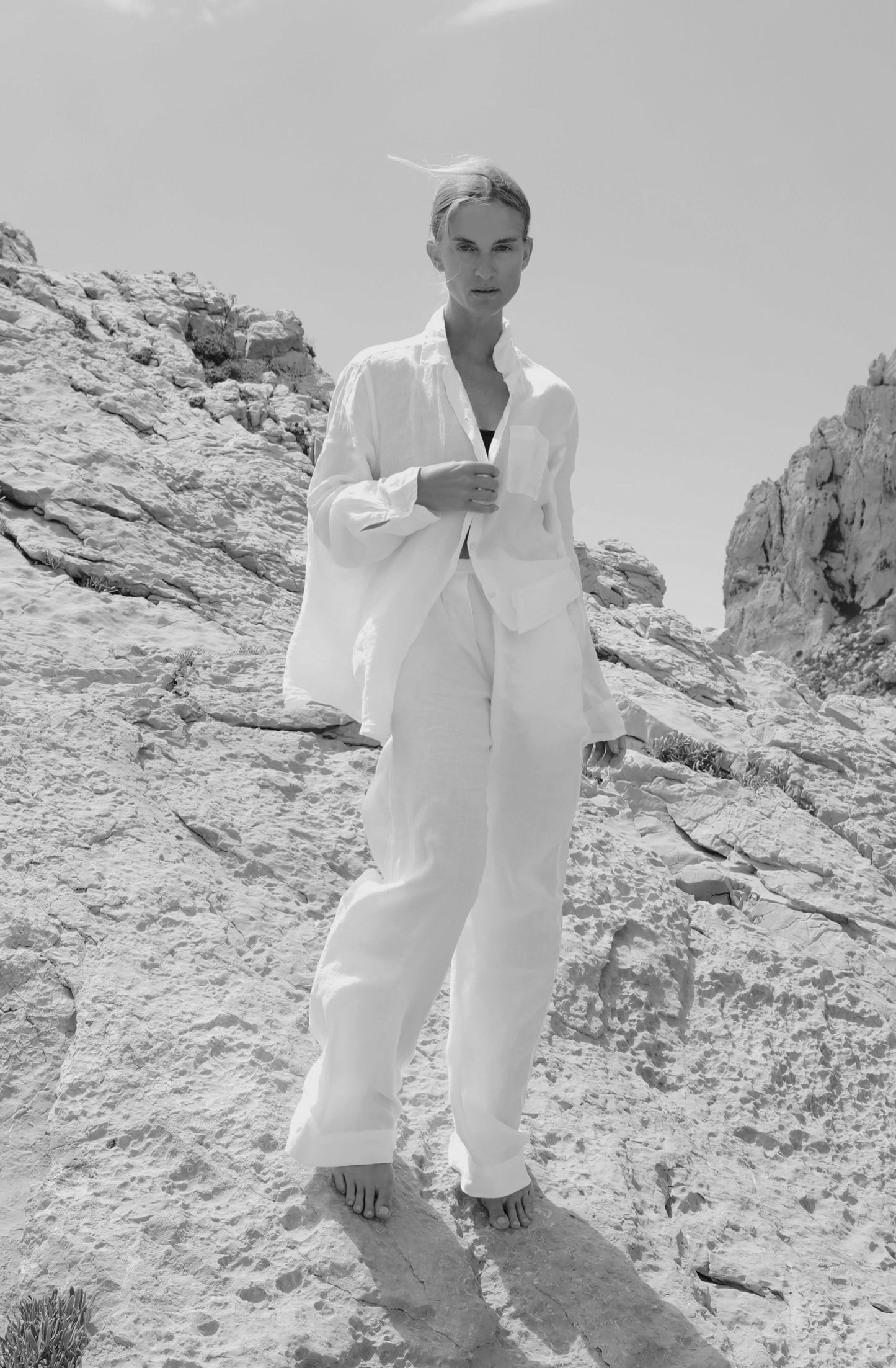 Description: A woman in a white suit, wearing Velvet by Jenny Graham's PICO PANT, soft linen pants with an elastic waistband, standing on a rock.-26829926334657