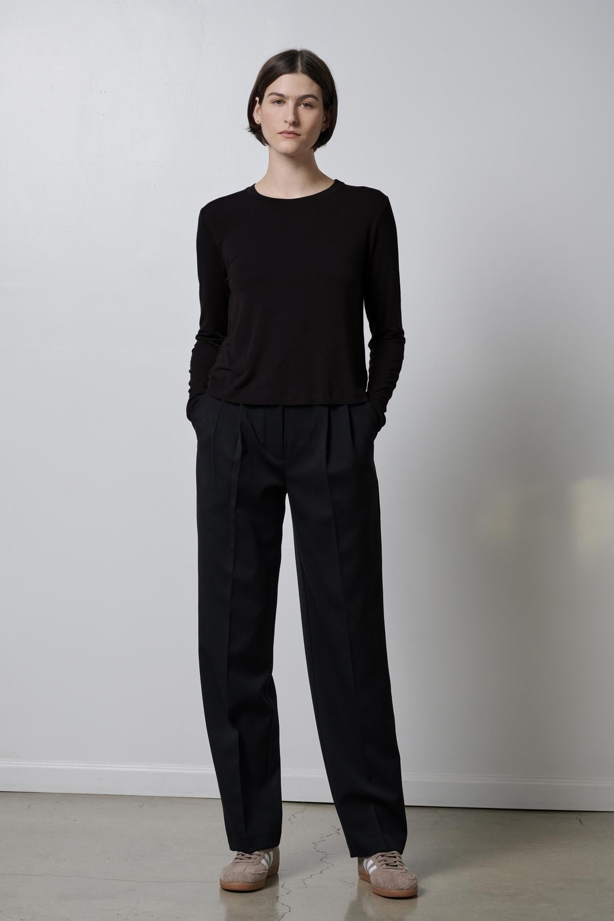   A woman wearing black rib knit trousers and a soft hand black Velvet by Jenny Graham sweater. 