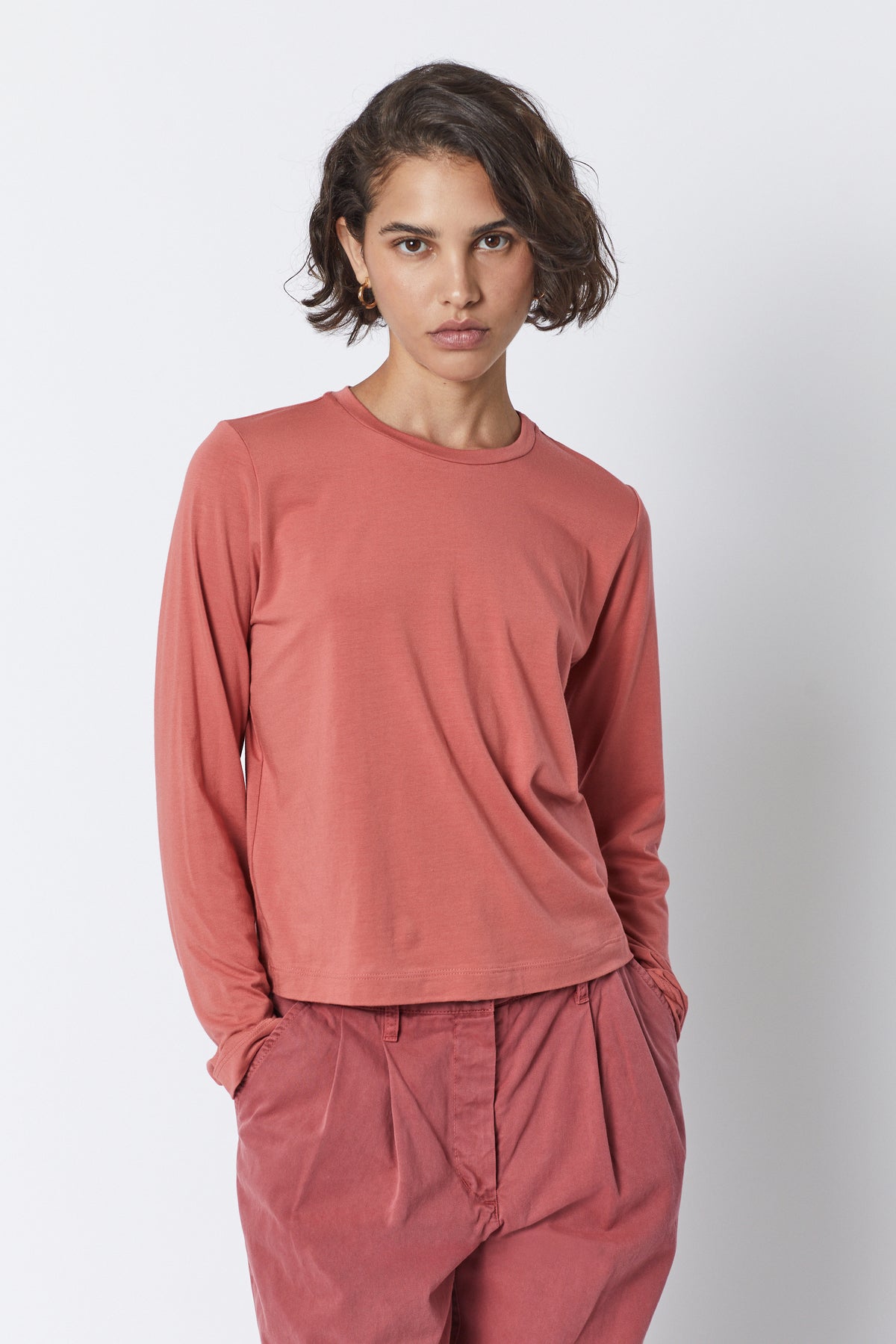   The model is wearing a Velvet by Jenny Graham pink long-sleeved PACIFICA TEE with a soft hand and pleated pants. 