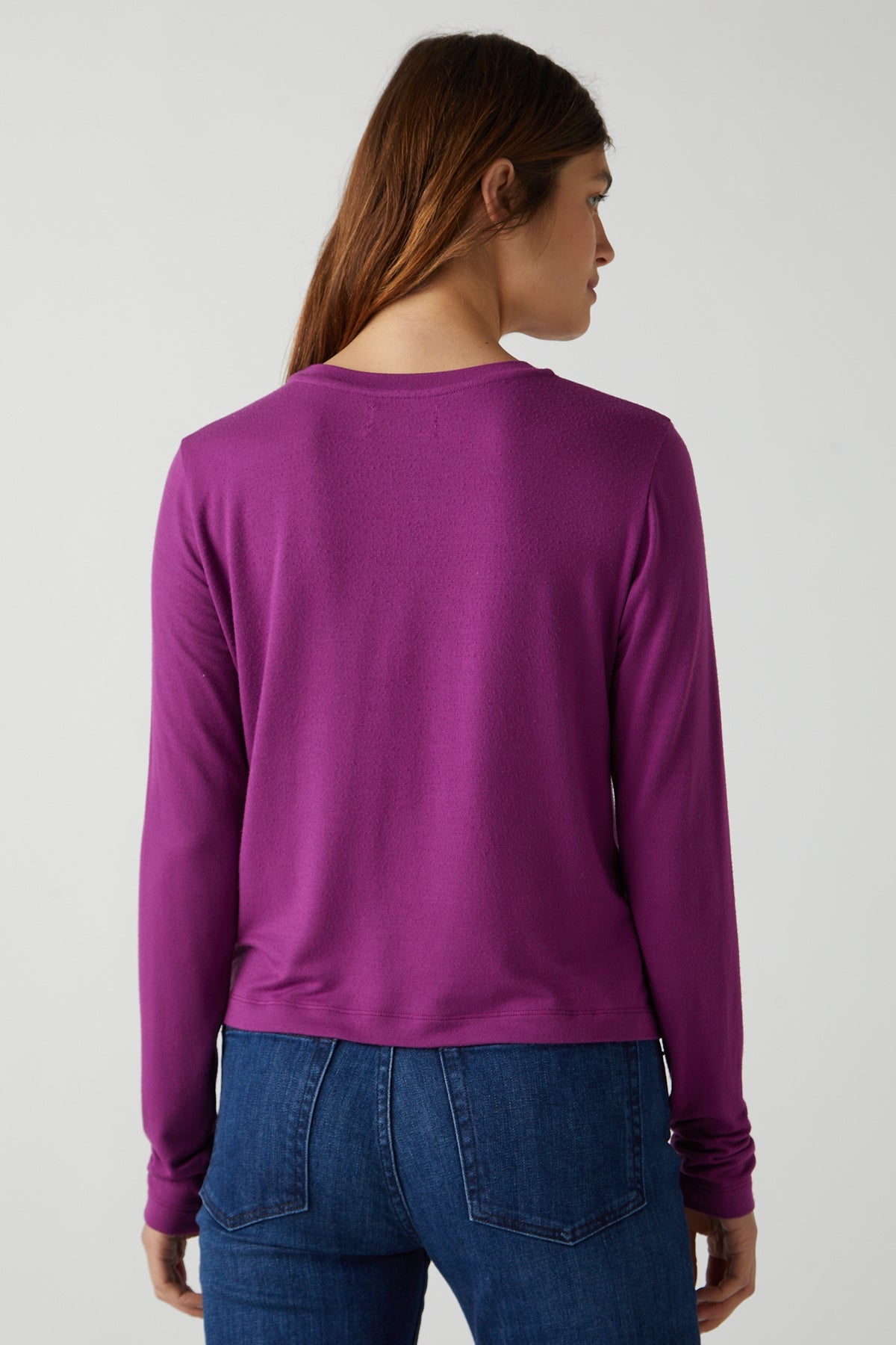   The back view of a woman wearing a Purple Pacifica Tee by Velvet by Jenny Graham and jeans. 