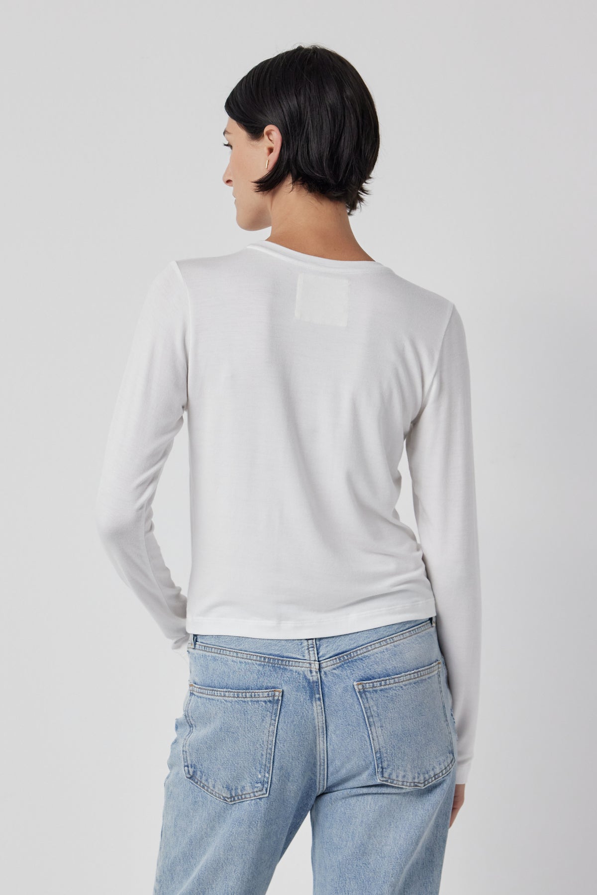 The back view of a woman wearing Velvet by Jenny Graham stretch jeans and a white long-sleeved Pacifica Tee.-35416710676673