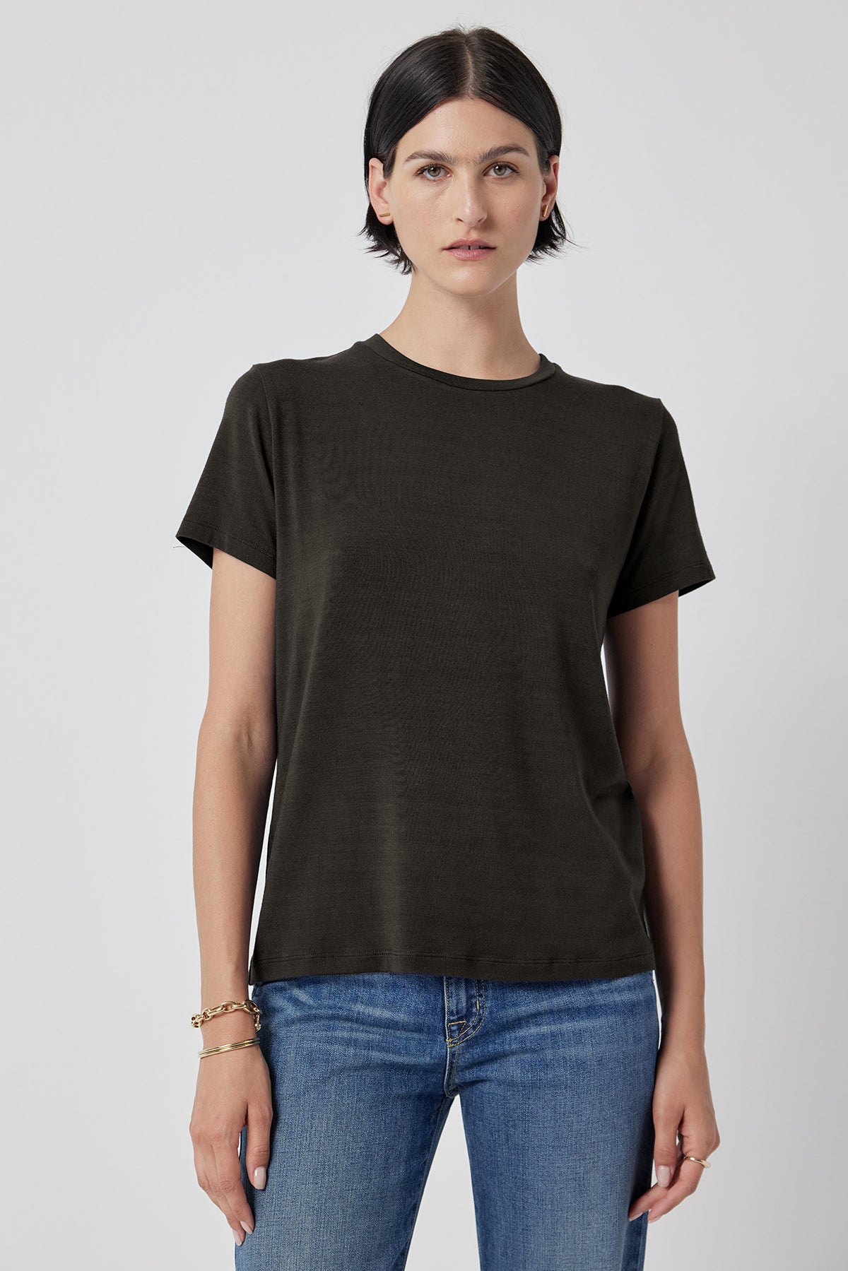   A woman in a Solana Tee by Velvet by Jenny Graham and blue jeans standing against a white background. 