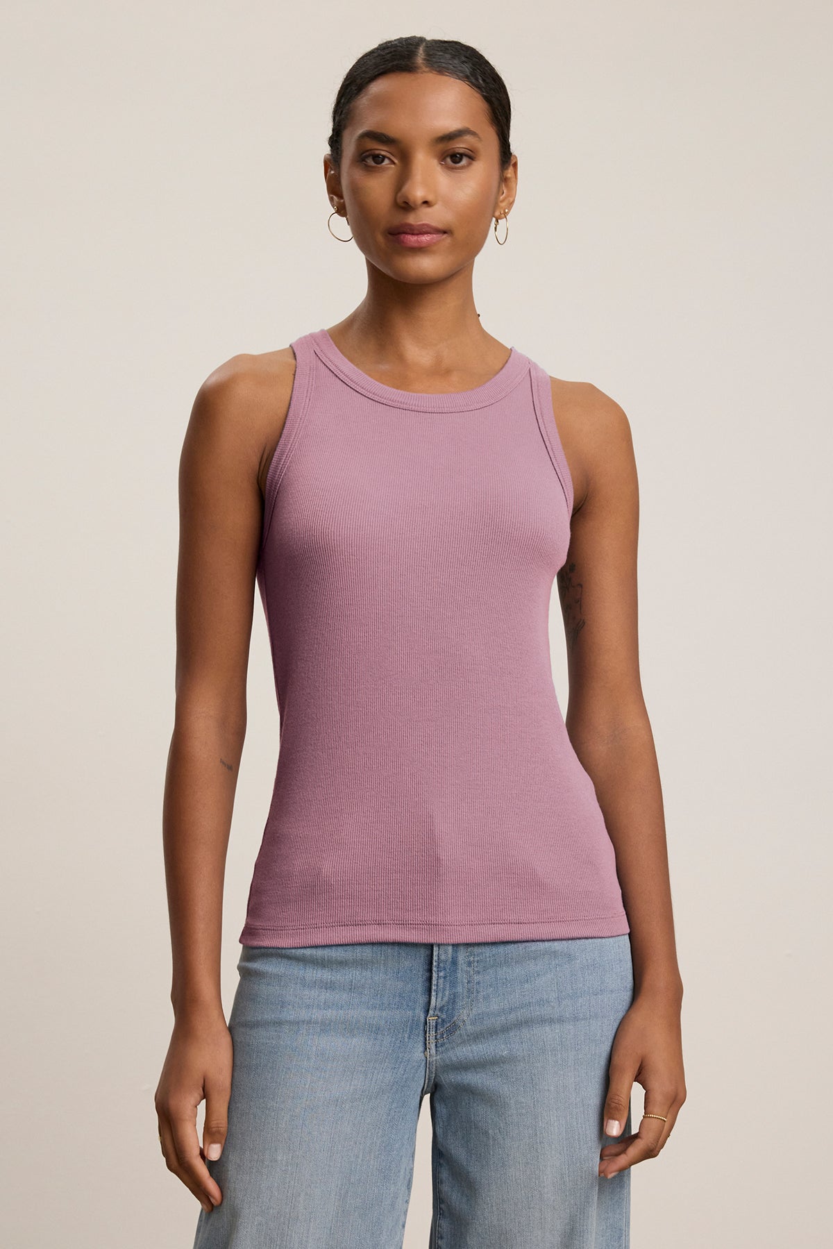   Against a plain background, a person wears the CRUZ TANK TOP by Velvet by Jenny Graham, effortlessly styled with blue jeans to showcase the essence of a capsule wardrobe. 