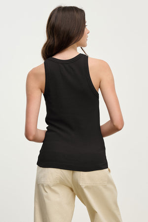 A person with long brown hair, facing away from the camera against a plain light background, wears the CRUZ TANK TOP by Velvet by Jenny Graham and beige pants, capturing a capsule wardrobe style.