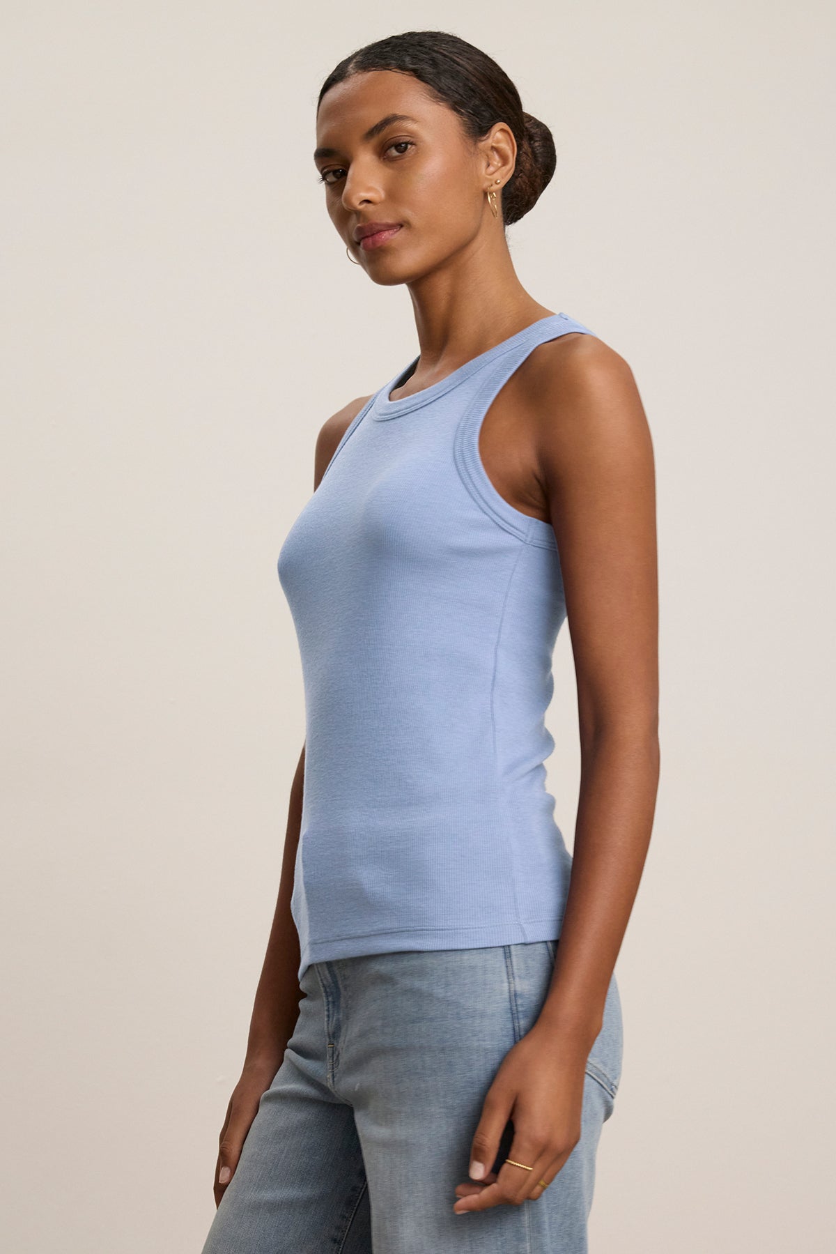   A person wearing the CRUZ TANK TOP by Velvet by Jenny Graham, a versatile light blue ribbed cotton-modal blend piece, pairs it with blue jeans against a plain background. 