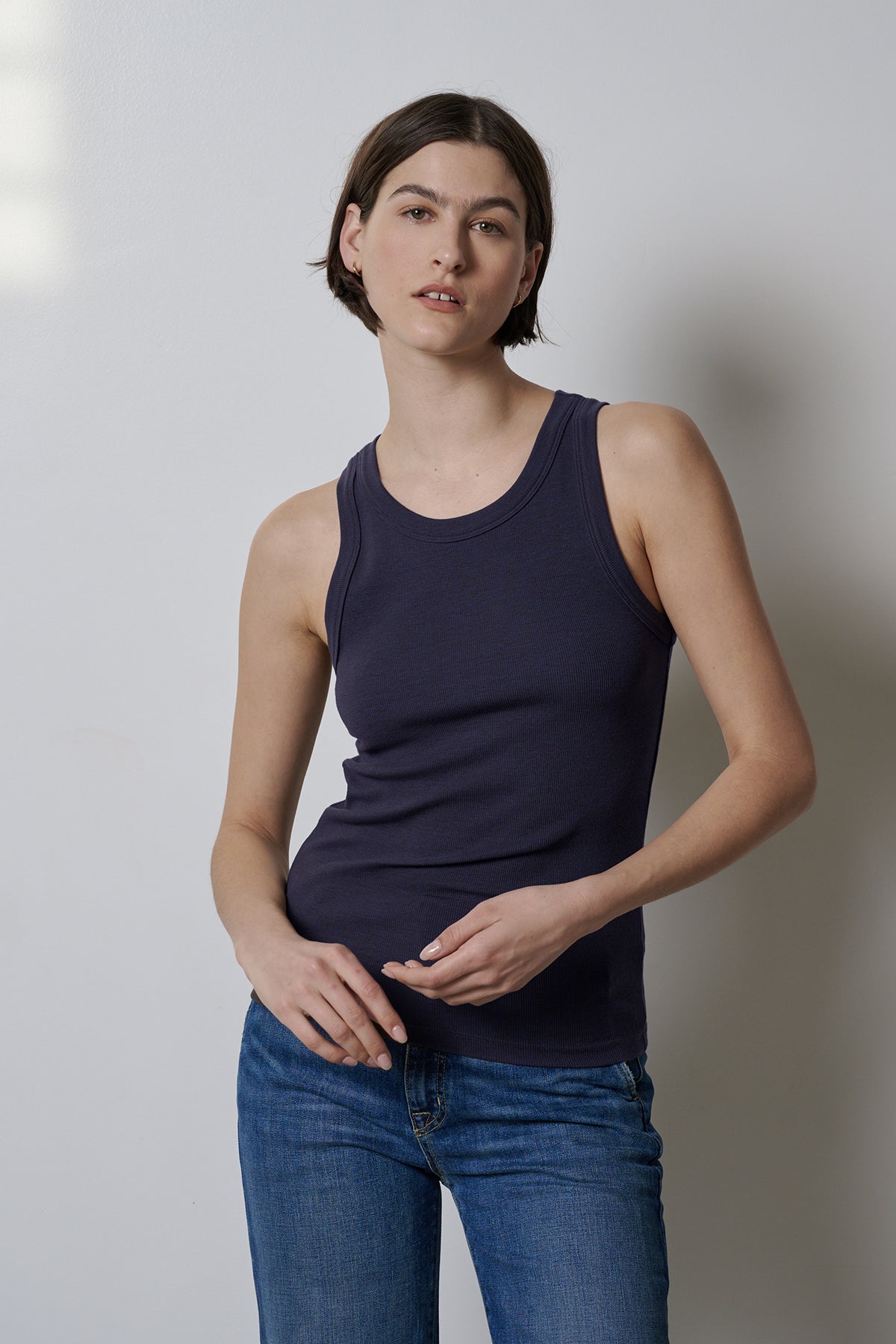 A woman wearing stretch jeans and a fitted Navy Velvet by Jenny Graham Cruz tank top.-35547434909889