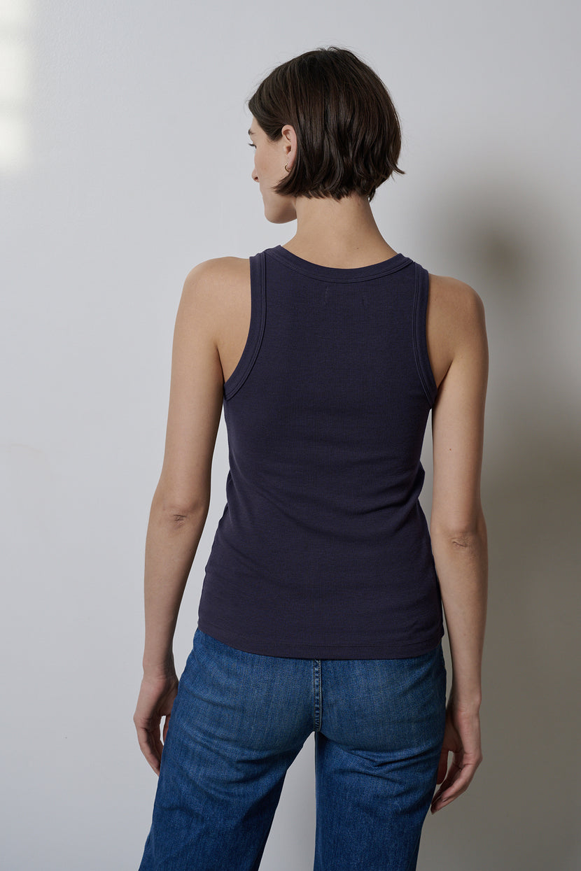The woman's back view showcases a form-fitting CRUZ tank top by Velvet by Jenny Graham paired with jeans that offer stretch for comfort.