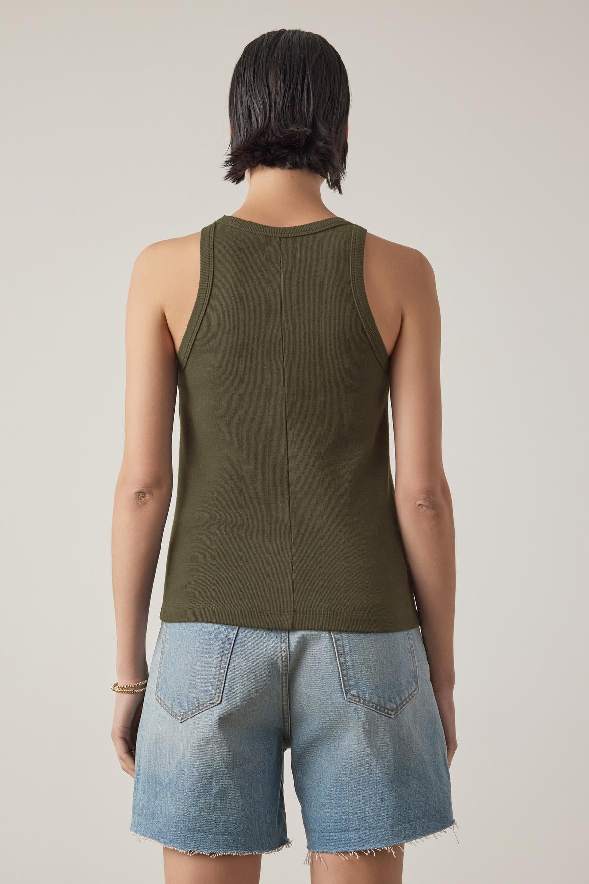   A person with short hair is seen from the back, wearing the green CRUZ TANK TOP by Velvet by Jenny Graham and light blue denim shorts. 