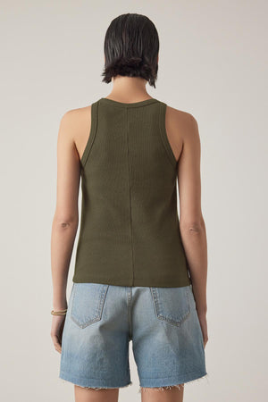 A person with short hair is seen from the back, wearing the green CRUZ TANK TOP by Velvet by Jenny Graham and light blue denim shorts.