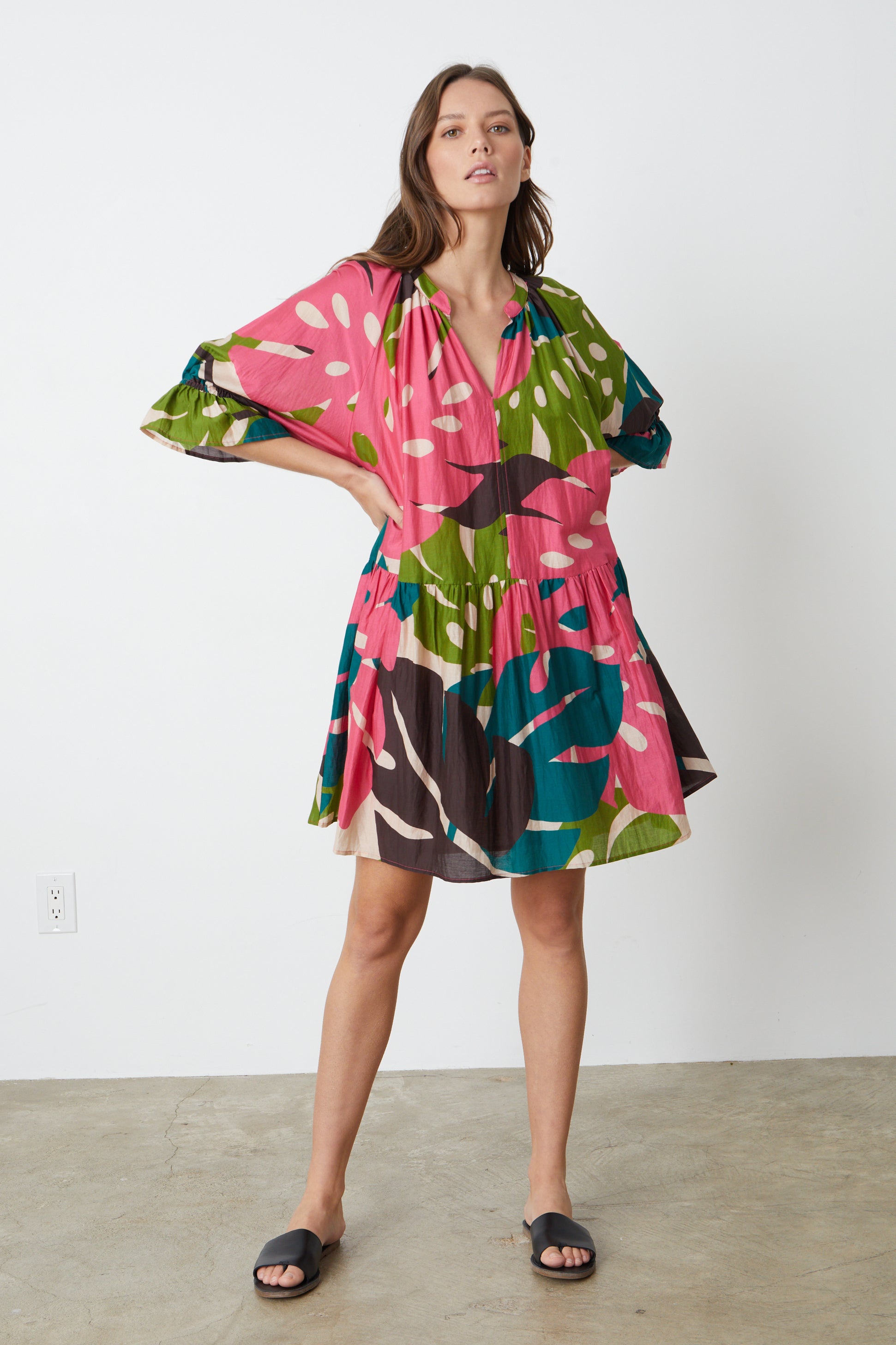   The model is wearing a Velvet by Graham & Spencer TRACY PRINTED DRESS with ruffles in bold colored Monstera print 