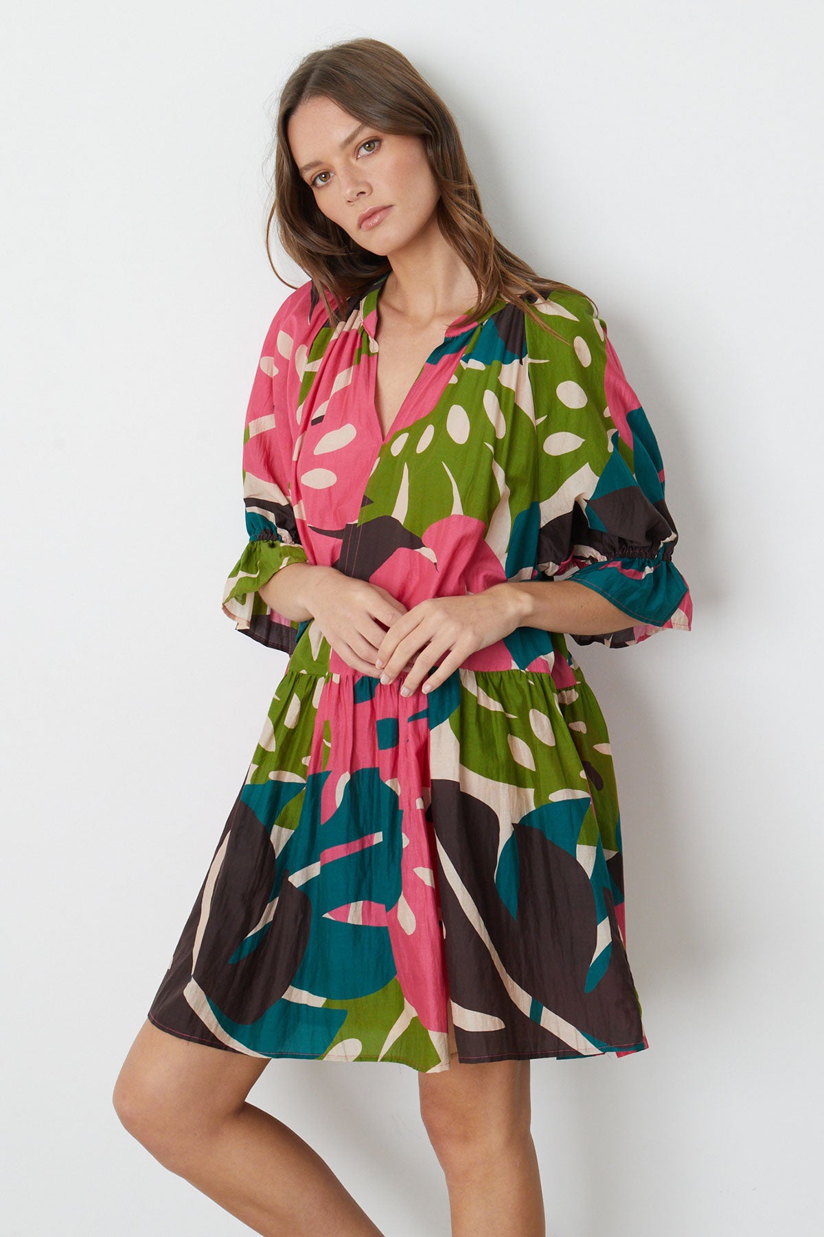   A model wearing a Velvet by Graham & Spencer TRACY PRINTED DRESS in bold colored Monstera print 