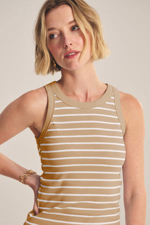 A woman with short blonde hair wears the MORIE TANK TOP by Velvet by Graham & Spencer—a beige and white striped, fitted cotton sleeveless top—paired with a gold bracelet, standing against a neutral background.