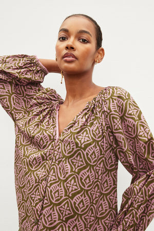 A woman wearing a boho-inspired Velvet by Graham & Spencer Marian Printed Button Front Top, styled in a chic ensemble featuring a green and pink patterned blouse.