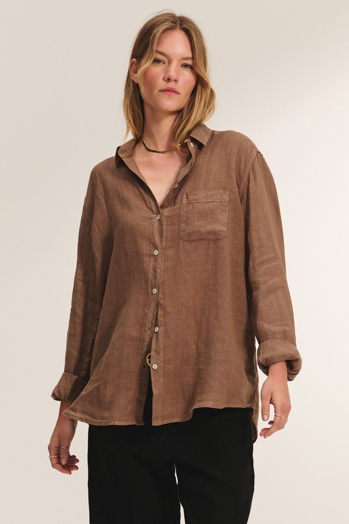 A woman models the MULHOLLAND LINEN SHIRT by Velvet by Jenny Graham, a relaxed-fit button-up with chest pocket and scooped hem, paired with black pants against a plain background.-39149230948545