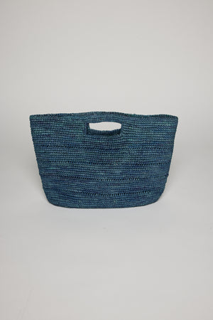 A blue Velvet by Graham & Spencer raffia straw basket with curved sides and an integrated handle, displayed against a white background.