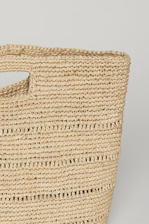 Close-up of a Velvet by Graham & Spencer Naomi Handheld Straw Bag featuring a sturdy handle and openwork design, against a neutral backdrop.