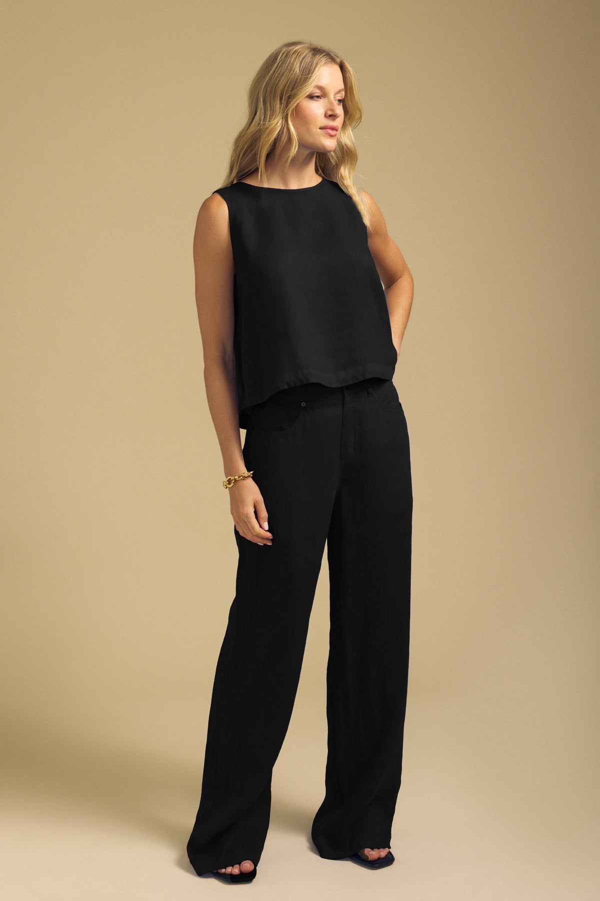 A woman wearing a black sleeveless top and black wide-leg NATALEN LINEN PANT.